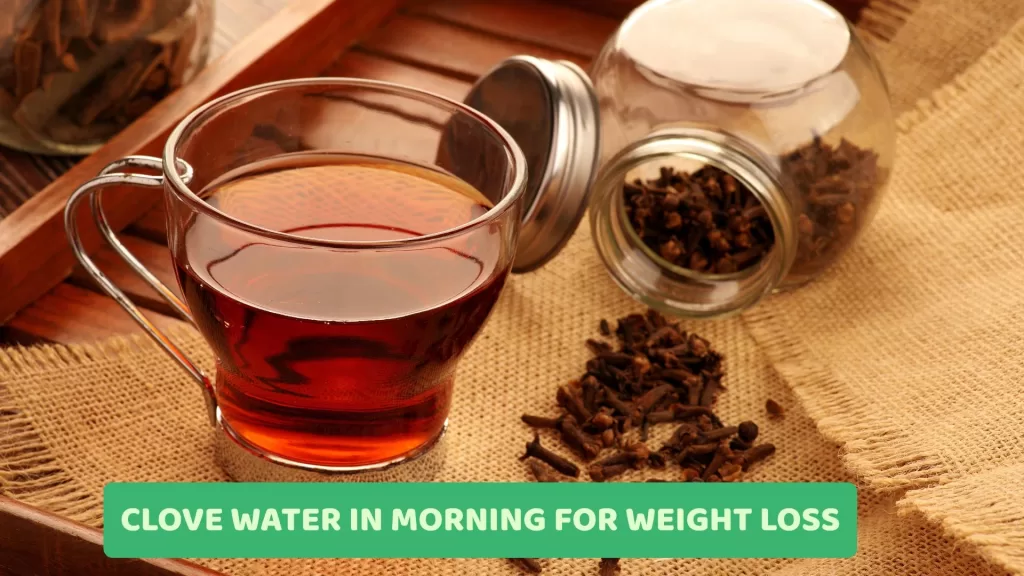 A glass of warm clove water on a wooden table, surrounded by whole cloves, symbolizes its morning weight loss benefits, like boosted metabolism, reduced bloating, and improved digestion.